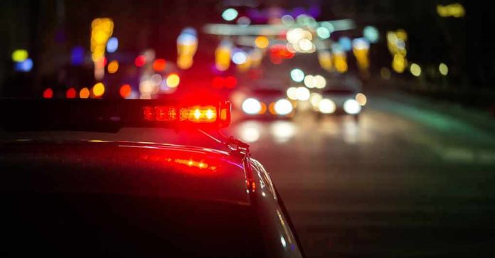 Police car with flashing red lights on a city street at night