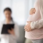 Pregnant woman holding belly during medical visit