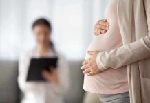 Pregnant woman holding belly during medical visit