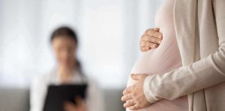 Pregnant woman holding belly during medical visit