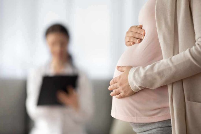 shutterstock_2043915227 Pregnant woman holding belly during medical visit