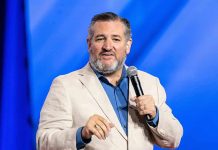 man in beige blazer speaking into a microphone