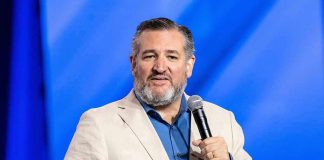 man in beige blazer speaking into a microphone