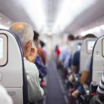 Laptop EXPLODES During Flight – Cabin Panic Airplane cabin aisle with passengers seated and seatback screens