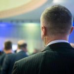 Top Defence Chief QUITS – Soldiers At Risk! Man with earpiece at a crowded event.