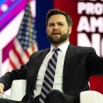 Mamdani Tries Retracting His ‘America Sucks’ July 4 Speech Man in suit speaking on stage during a panel discussion