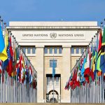 Mamdani INVESTIGATED After Iran Leader Meeting! United Nations building with numerous national flags outside.