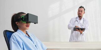 Patient wearing VR headset sits as doctor observes with tablet