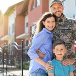Military family posing together outside a suburban home