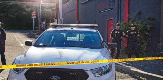 Aaron Guiel near police car behind yellow caution tape