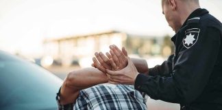 Police officer detains person against car