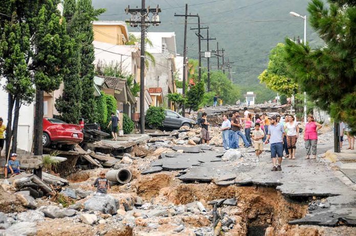 shutterstock_1165722466 Residents walk along a heavily damaged street after a disaster