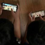 Kids Hired To Kill – Recruitment SWEEPS Nation! Two children playing mobile games side by side on the floor