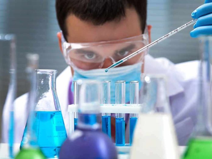 Scientist pipetting blue liquid into test tubes
