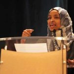 Ilhan Omar speaking at a podium with a microphone