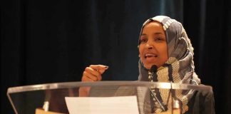 Ilhan Omar speaking at a podium with a microphone