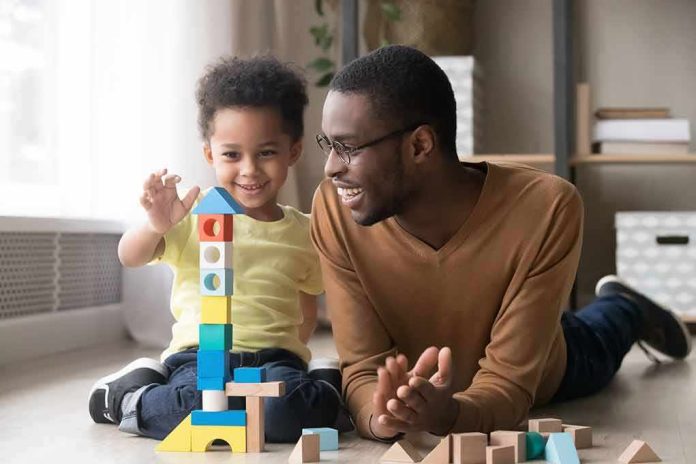 Father and child building a tall tower with colorful wooden blocks on the floor