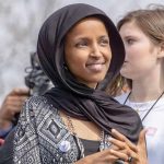 ICE Moves On Omar – Trump Confirms Details Ilhan Omar wearing a black headscarf at an outdoor event