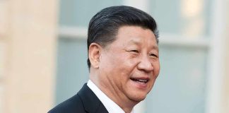 Trump Has Xi In STITCHES Over Biden Pic man in suit smiling outdoors