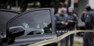 Car door with bullet holes at a taped-off crime scene
