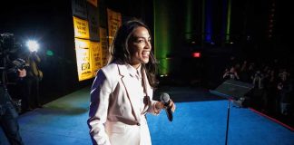 Woman in a light suit holding a microphone on a stage