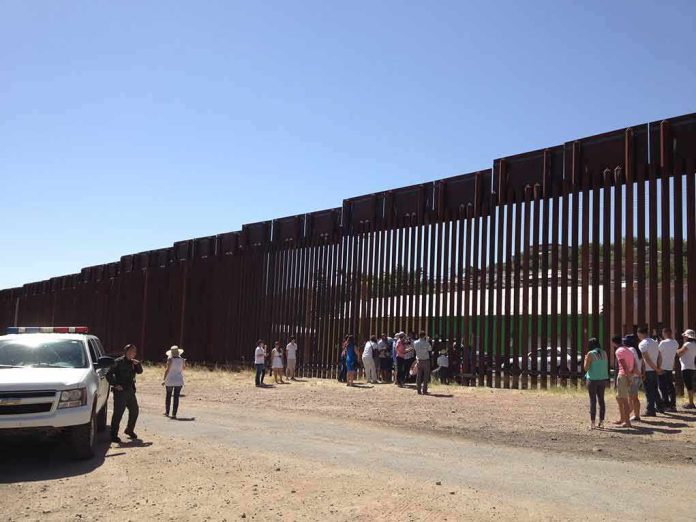 Border fence with group of people and a patrol vehicle