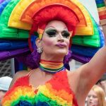 Drag performer in vibrant rainbow costume at a parade