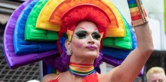 Drag performer in vibrant rainbow costume at a parade