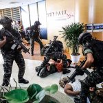 Tactical police detain suspects in an office lobby