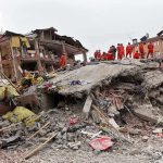 Rescue workers in orange uniforms on a collapsed building site after an earthquake
