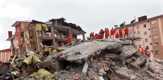 Rescue workers in orange uniforms on a collapsed building site after an earthquake