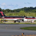 Private jet with black and red livery parked on airport tarmac