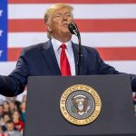 Donald Trump speaks at a podium with U.S. flag backdrop; Christian Jones, Caraun Reid, and Bill Bergey in crowd
