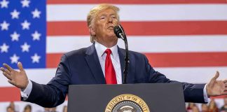 Donald Trump speaks at a podium with U.S. flag backdrop; Christian Jones, Caraun Reid, and Bill Bergey in crowd
