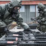 Shock Deal: Hamas Disarms, Gaza Handed Over Personnel in hazmat suits decontaminating rifles on an outdoor table