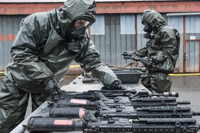 shutterstock_1711796473 Personnel in hazmat suits decontaminating rifles on an outdoor table
