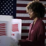 Voter at a polling booth with an American flag backdrop