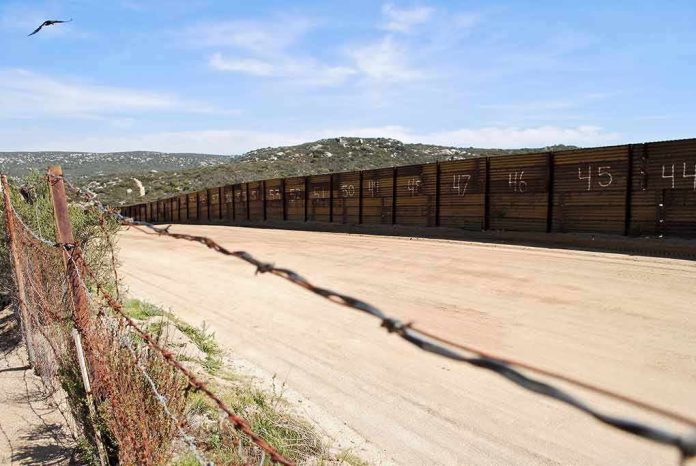 Border fence along dirt road in arid landscape