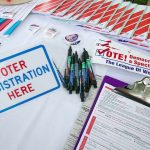 Mike Lindell’s SURGES Ahead In Hotly Contested Governors Race Voter registration table with forms, pens, and informational materials