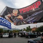 Memorial Day Tragedy – Veteran Viciously ASSAULTED! Large political flag over street protest with police and cars below