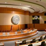 PASSED: Child Predators Allowed On Ballots Interior view of a government chamber with wooden paneling and seating