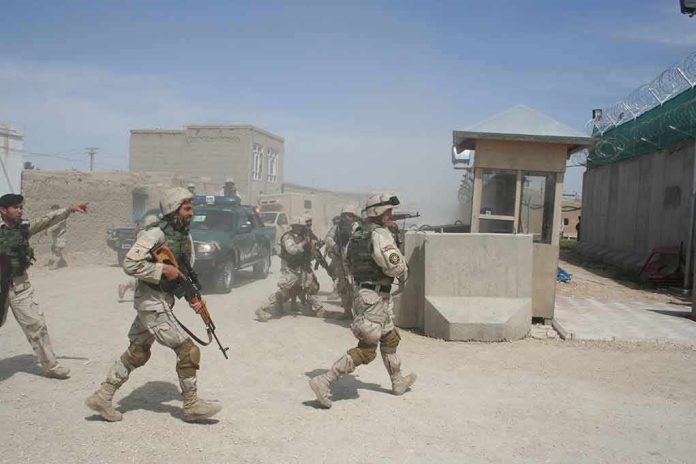 shutterstock_1931171405-1 Soldiers in desert uniforms run past a checkpoint amid dust