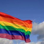 Rainbow pride flag waving against a blue sky