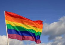 Rainbow pride flag waving against a blue sky