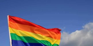 Rainbow pride flag waving against a blue sky