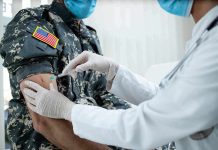 Healthcare worker giving vaccine to person in military uniform