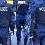 Riot police officers in protective gear holding shields