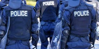 Riot police officers in protective gear holding shields