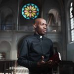Priest speaking with a visitor inside a church