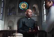 Priest speaking with a visitor inside a church